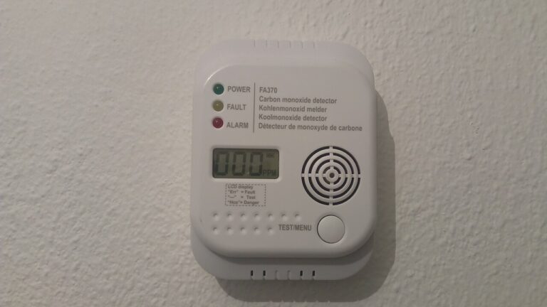White wall-mounted carbon monoxide detector with a digital display reading 000 PPM, power, fault and alarm lights, and a test button