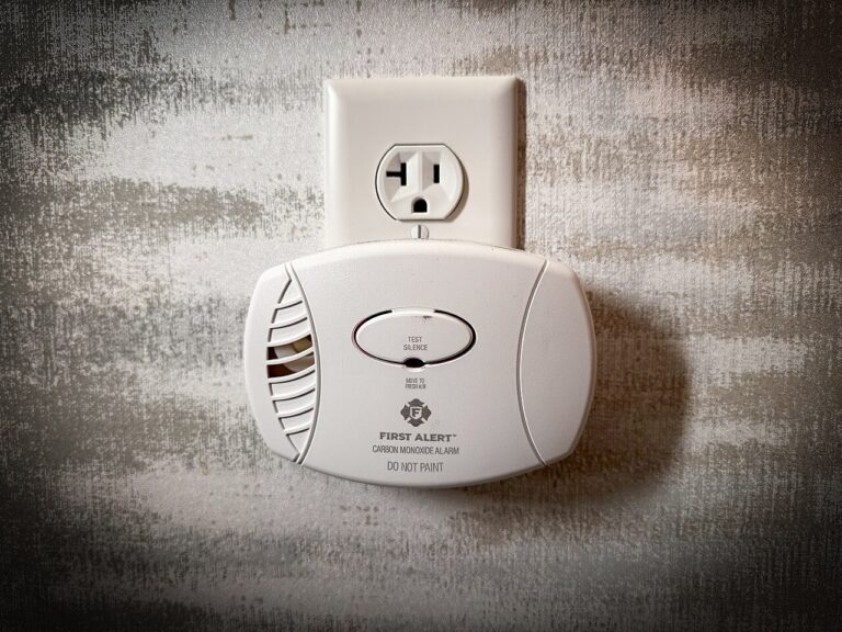 White plug-in carbon monoxide alarm mounted on a wall outlet