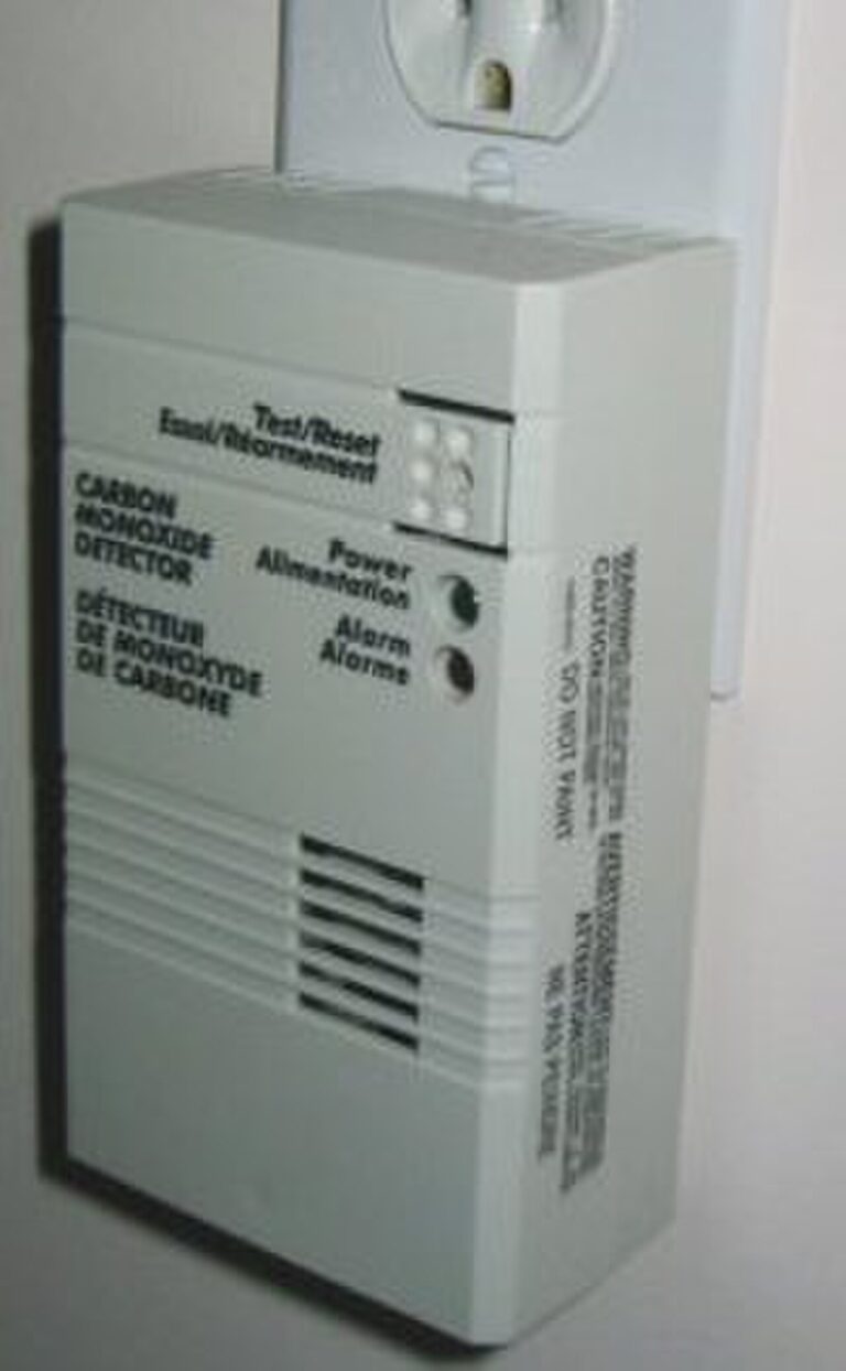 Plug-in carbon monoxide detector with test button and alarm lights mounted in a wall outlet